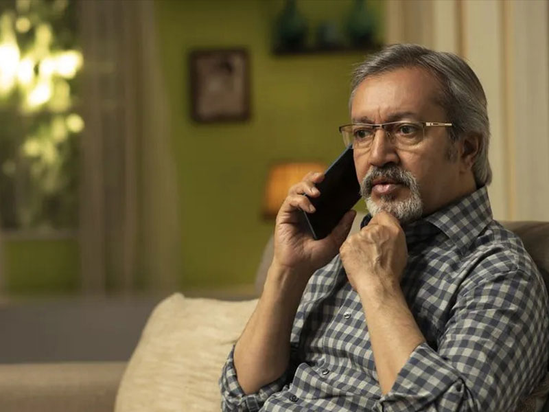 Asian man sat on sofa with phone