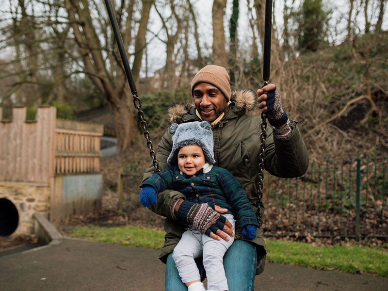 Man swinging with son in play park