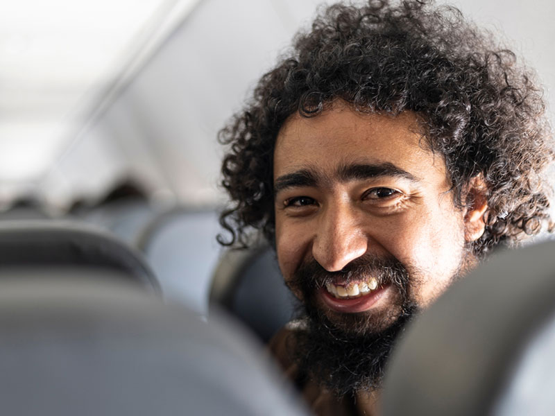 Man with curly hair looking back over aircraft seats