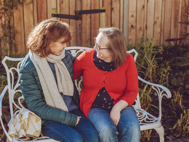 Friends sat on bench hugging