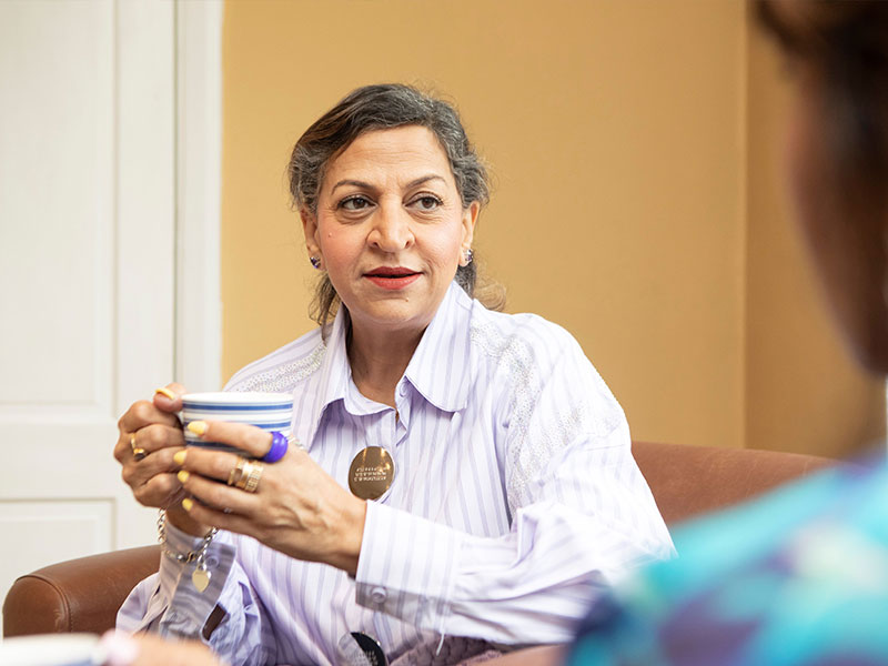 Woman in lilac shirt having cup of tea