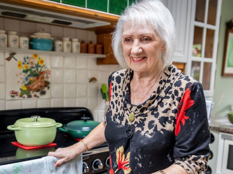 Woman with red lipstick and white hair in kitchen